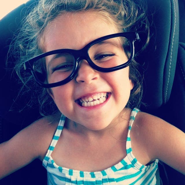 The photo the character was drawn from: a grinning girl with curly hair and big black glasses.
